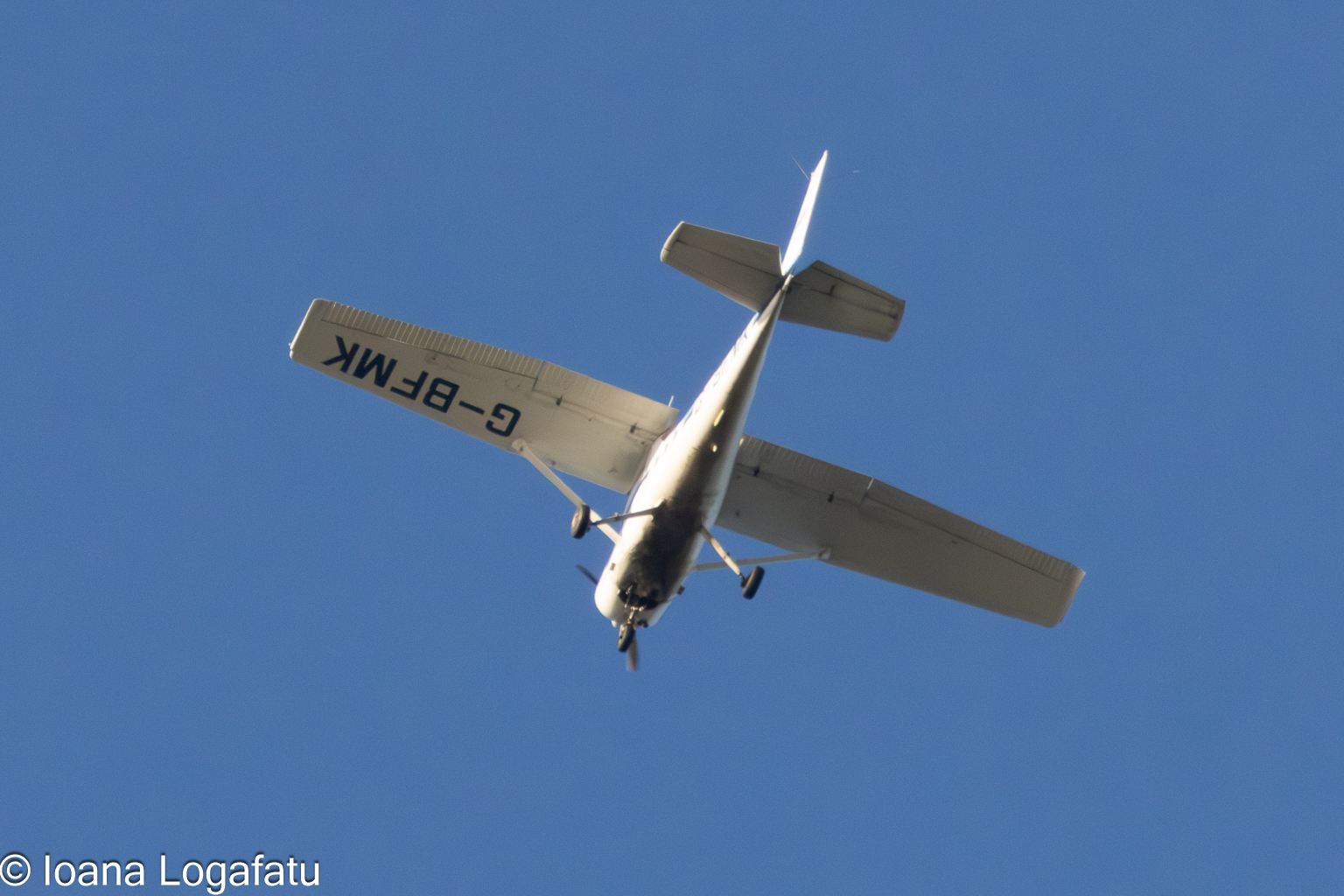 Small aircraft soars high against blue sky